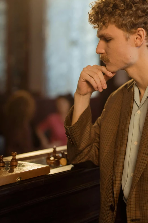 a man with curly hair sitting at a chess board