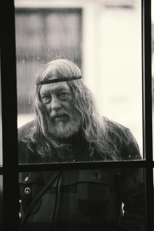 a man with long hair looking out a window