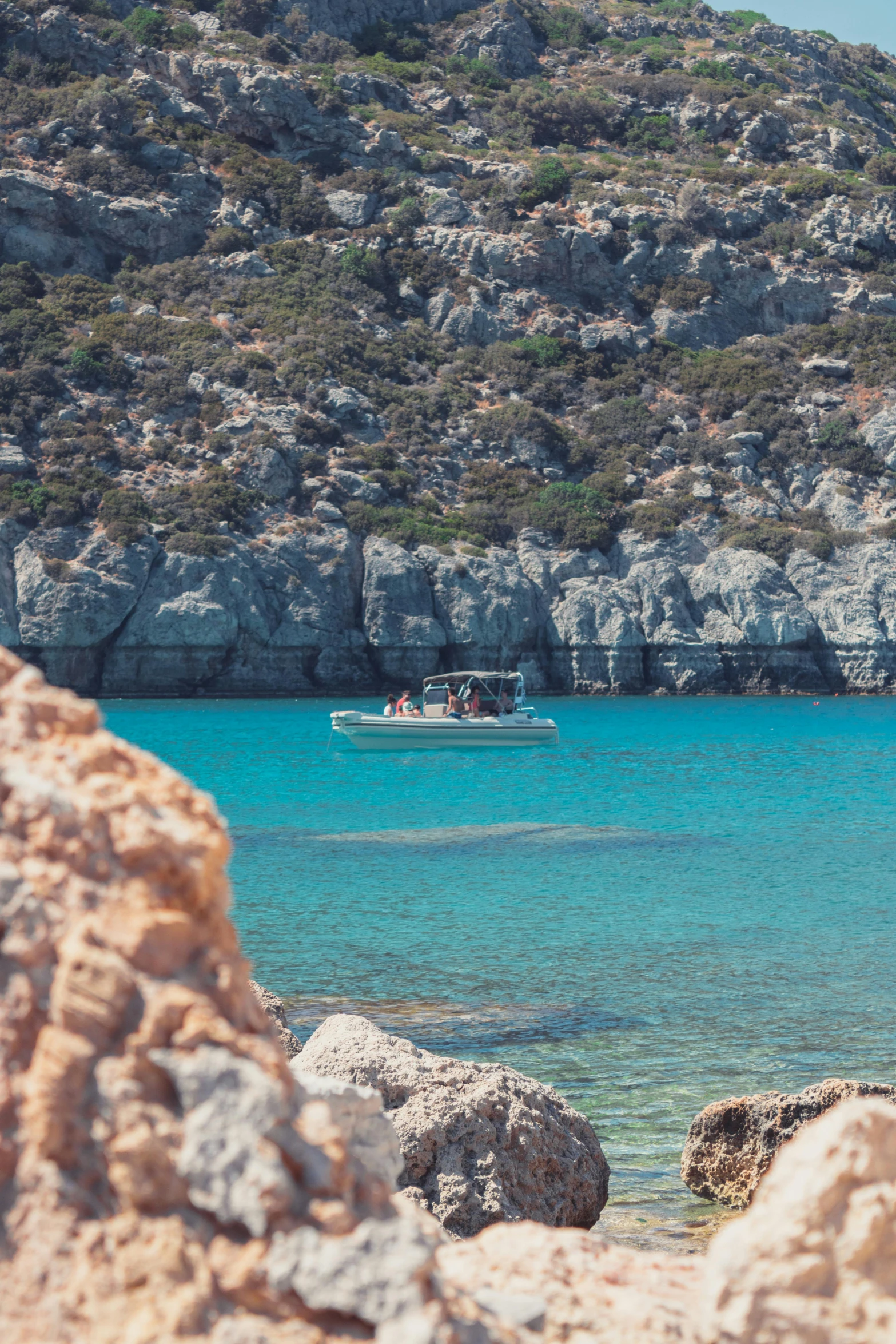 a fishing boat passing by near the rocky shore