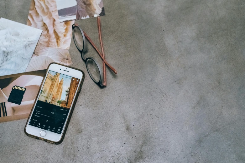 an iphone and some papers and reading glasses