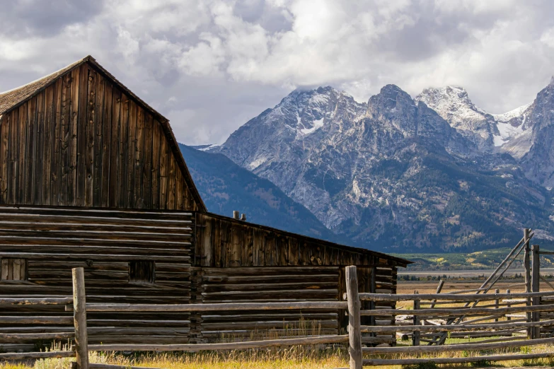 a large farm shed and mountains on the background