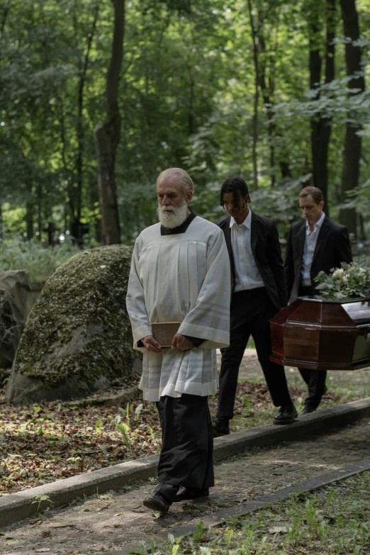 a man with an old fashioned white coat walking across a park