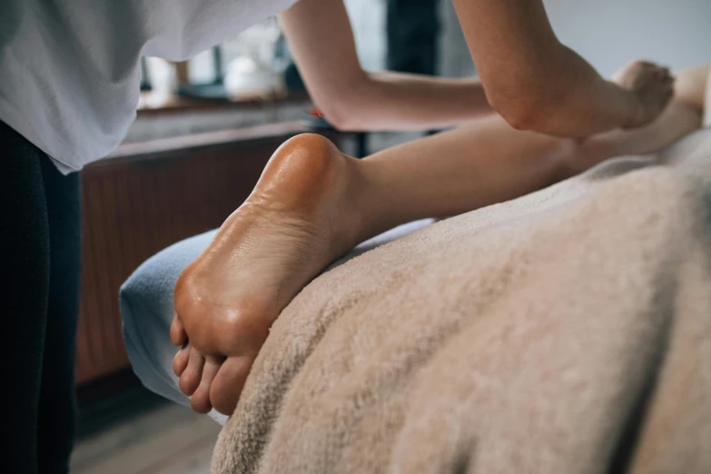 the foot is sitting on the bed, being touched by a person