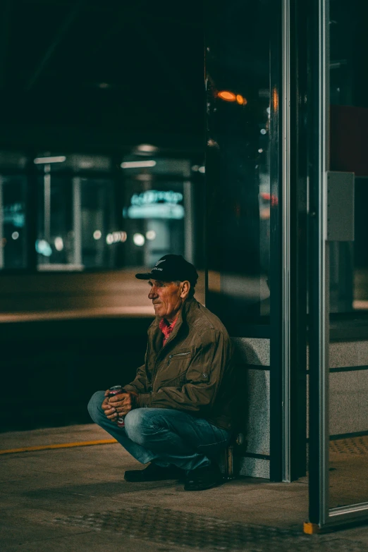 a man sits on the sidewalk at night by himself