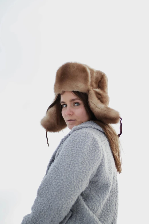 woman with grey shirt, light gray sweater and tan hat