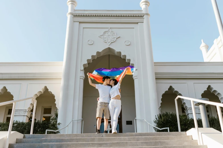 two women hold up a colorful umbrella while standing on the stairs