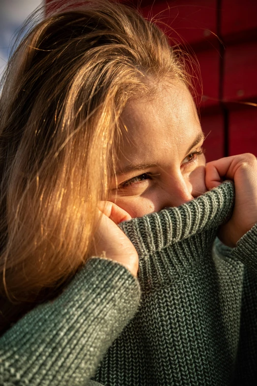 a person wearing a sweater covering their face