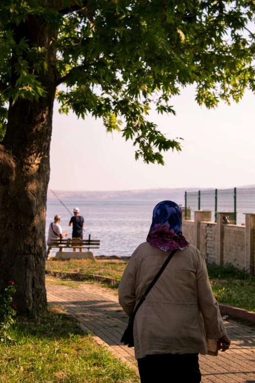 a woman is walking towards the ocean while others walk in the distance