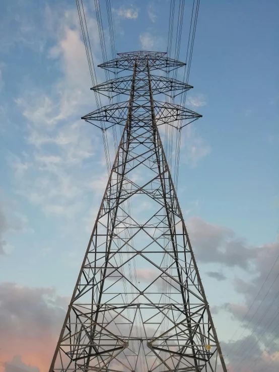 a tall tower with many wires and an airplane flying overhead