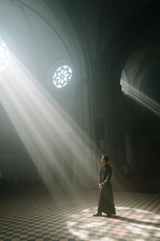 a man standing in the light coming through two circular windows
