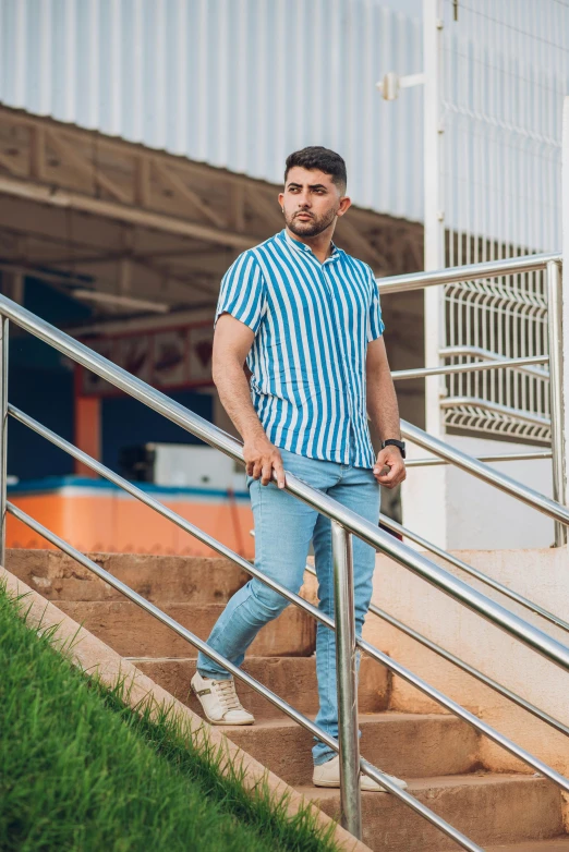 a man in striped shirt and jeans walking up the stairs