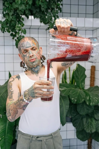 a man with tattoos is holding a juicer full of 