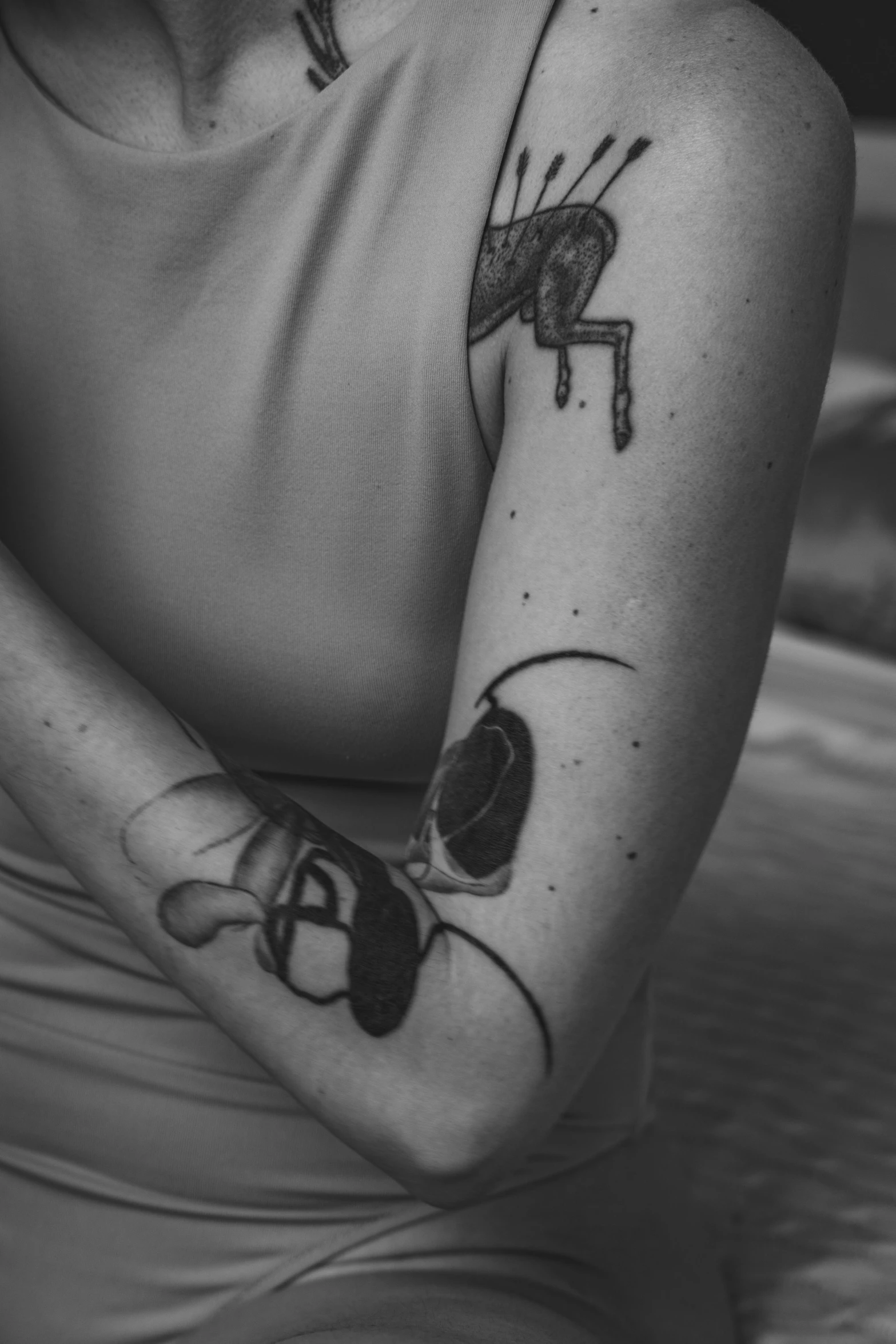 black and white pograph of someone's arm with an insect tattooed on it