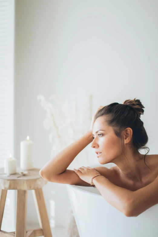 a young woman in a bathtub by a candle