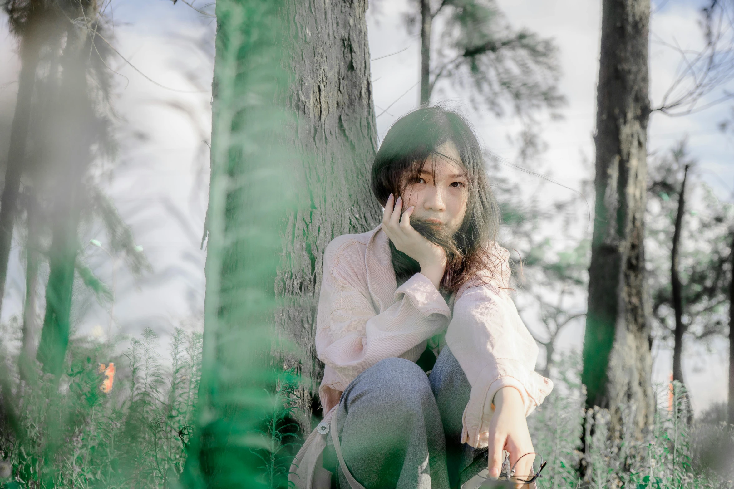 a girl sitting on the ground next to a tree