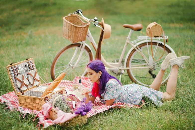 a little girl laying on a blanket near a bicycle