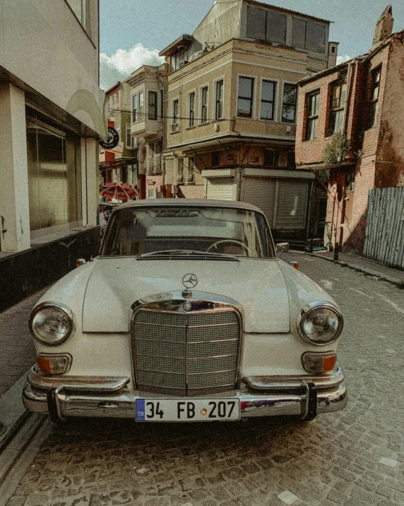 an old car parked in the middle of a narrow street