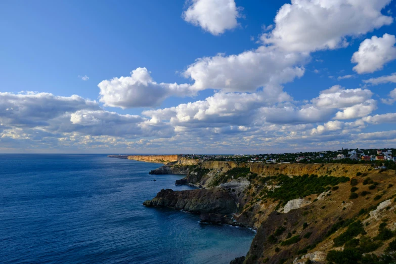 clouds hovering over the water and mountains beside a coastline