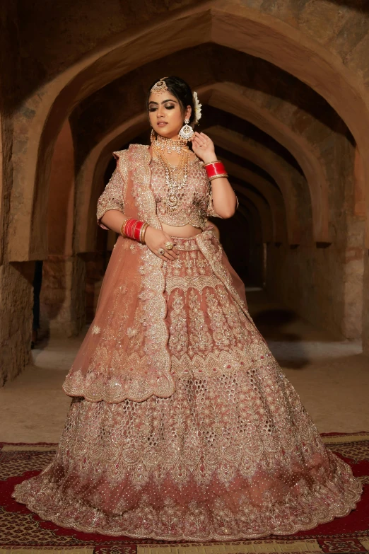 a woman in a pink gown poses in an archway