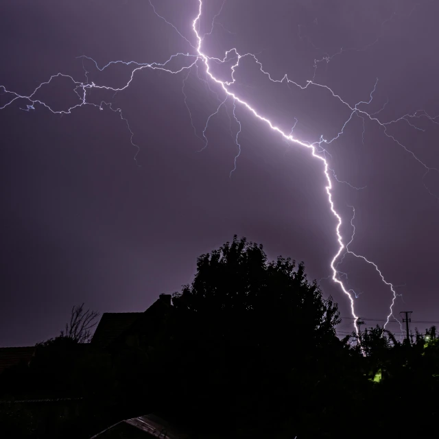 lightning strikes above a residential neighborhood in the night