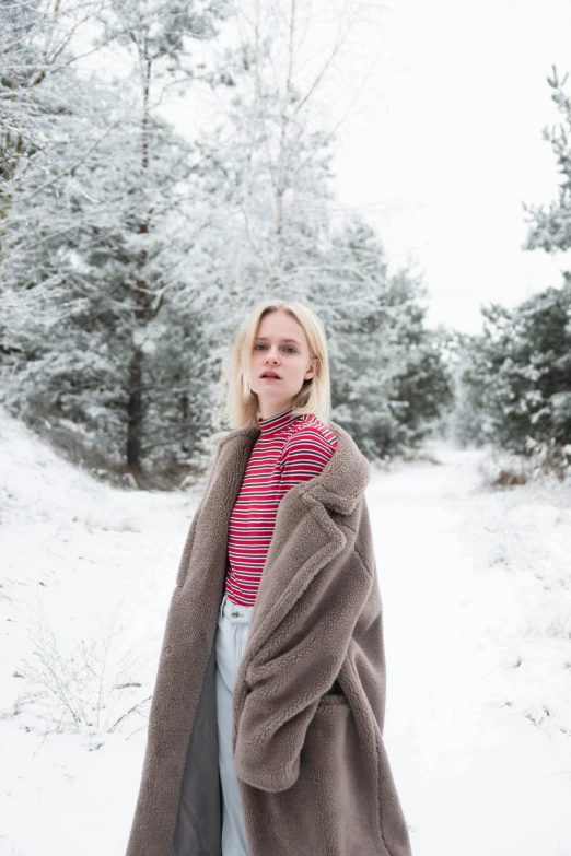 a woman stands in the snow in front of trees