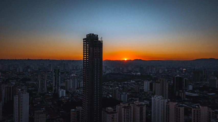 the sun sets behind some tall buildings in the city