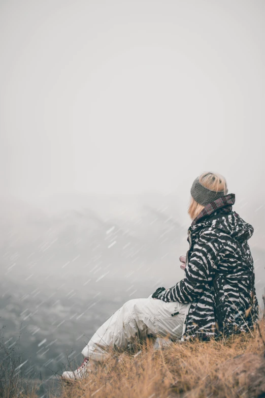 a person sitting on a hill, on a foggy day