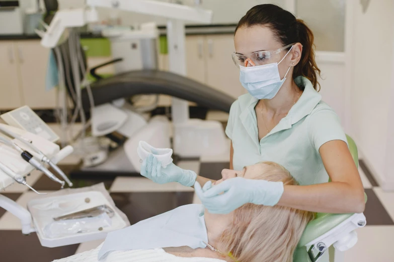 a woman is sitting in a dentist chair wearing glasses and a mask