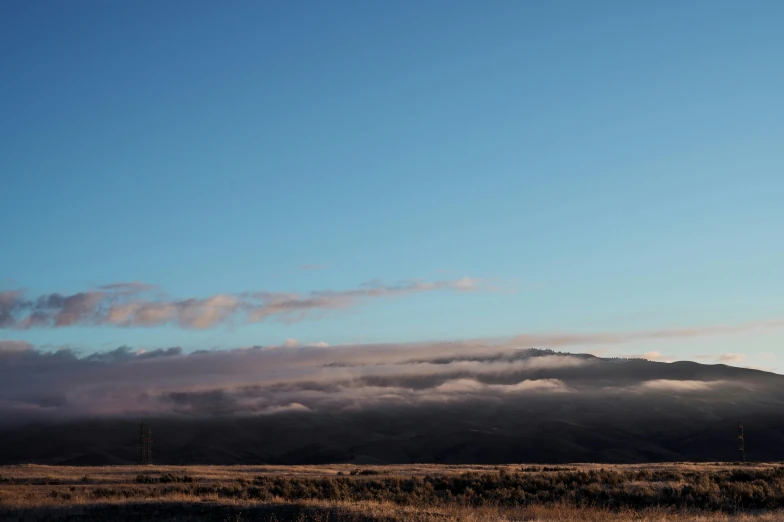 a large, low mountain is in the distance with some clouds