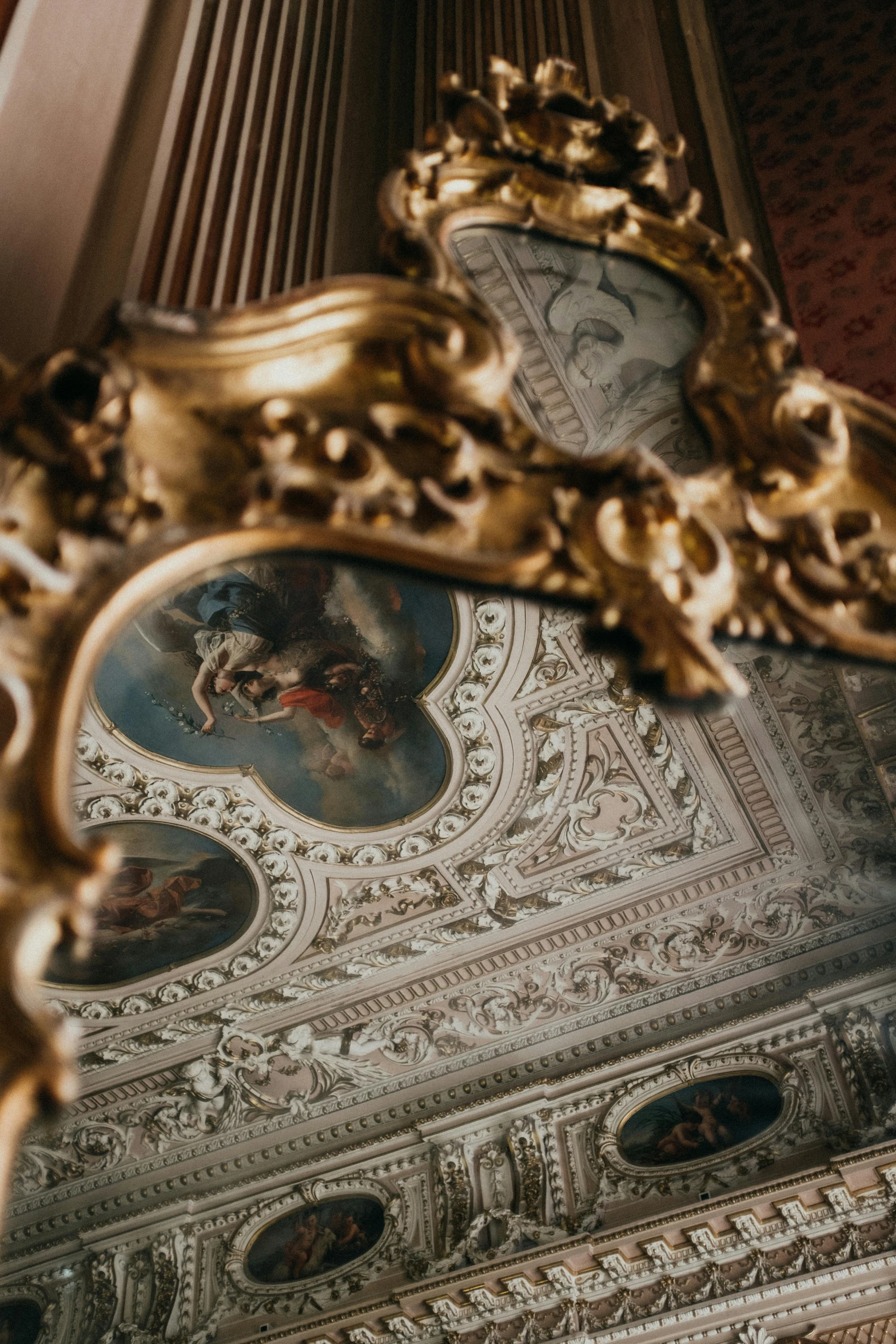 ornate gold frame around clock and wall painting in building