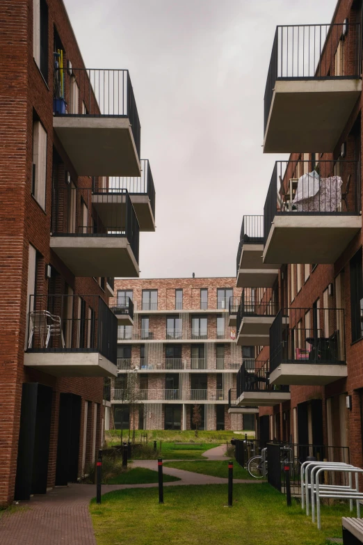 a small lawn surrounded by two brick apartment buildings