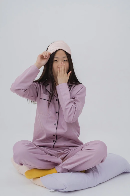 a woman in a pink pajama set sitting on the ground