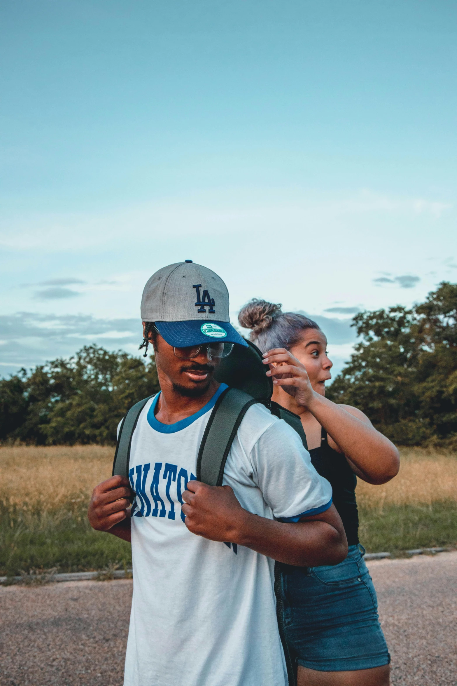 two young people with backpacks on the side of a road