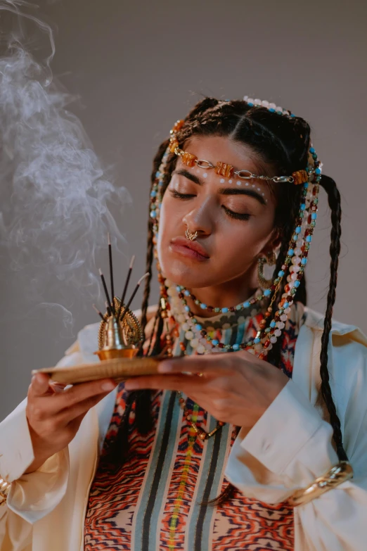 an indian woman wearing a white shirt and headdress is holding a pipe