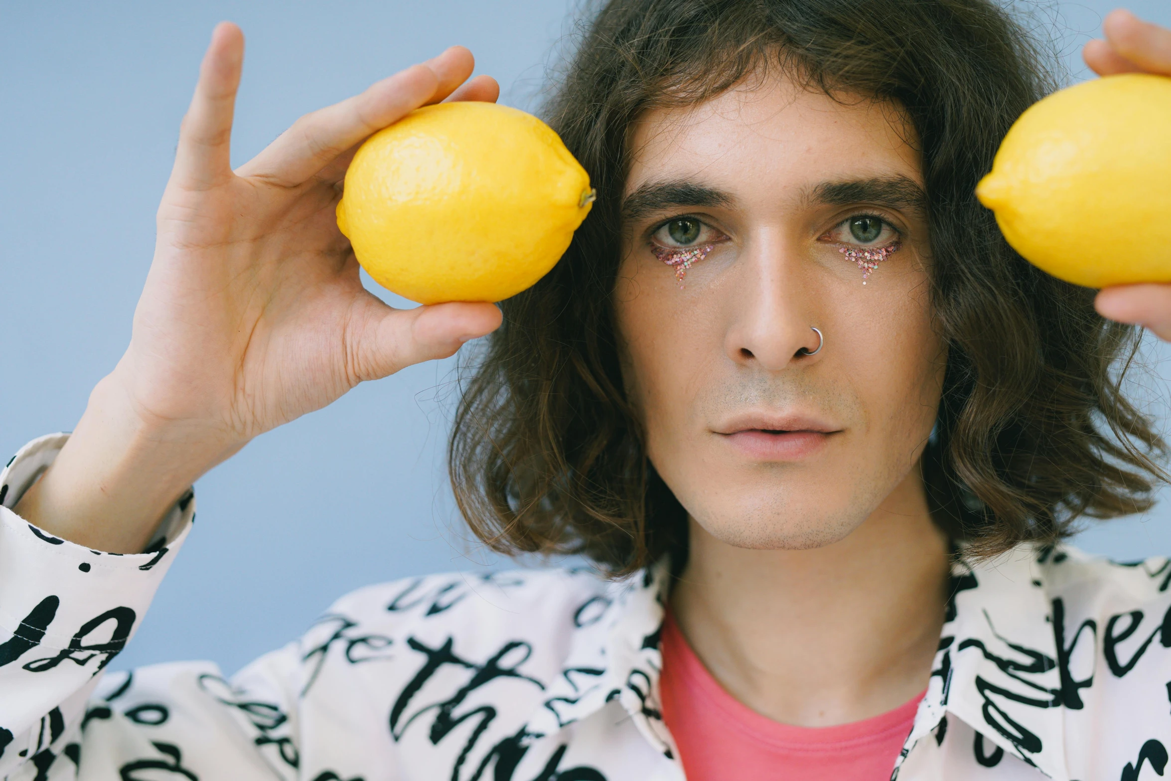 the man has long hair and he is holding a lemon