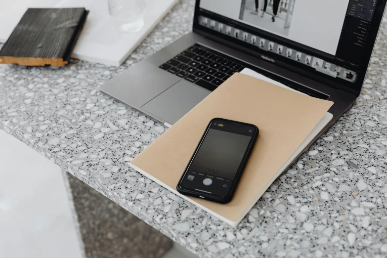 a phone, binder, book and laptop on the table