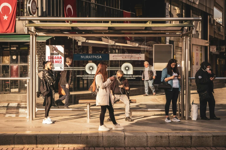 people wait at an outdoor covered bus stop