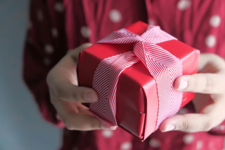 a close up of a person holding a red gift box