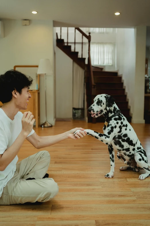 a young man crouching down with a dog standing next to him