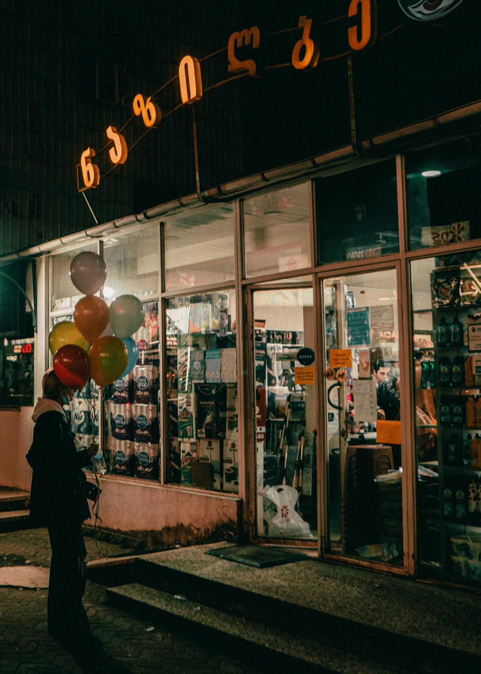 a woman walks on a sidewalk next to a building at night