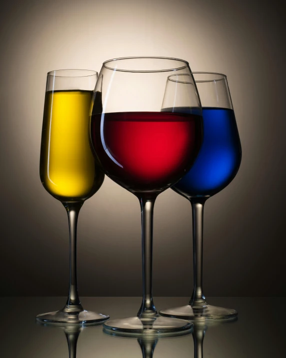 three glasses of different colors sit next to each other