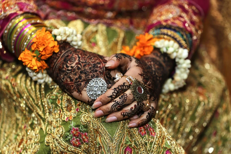 a person is wearing gold and holding hands with orange flowers