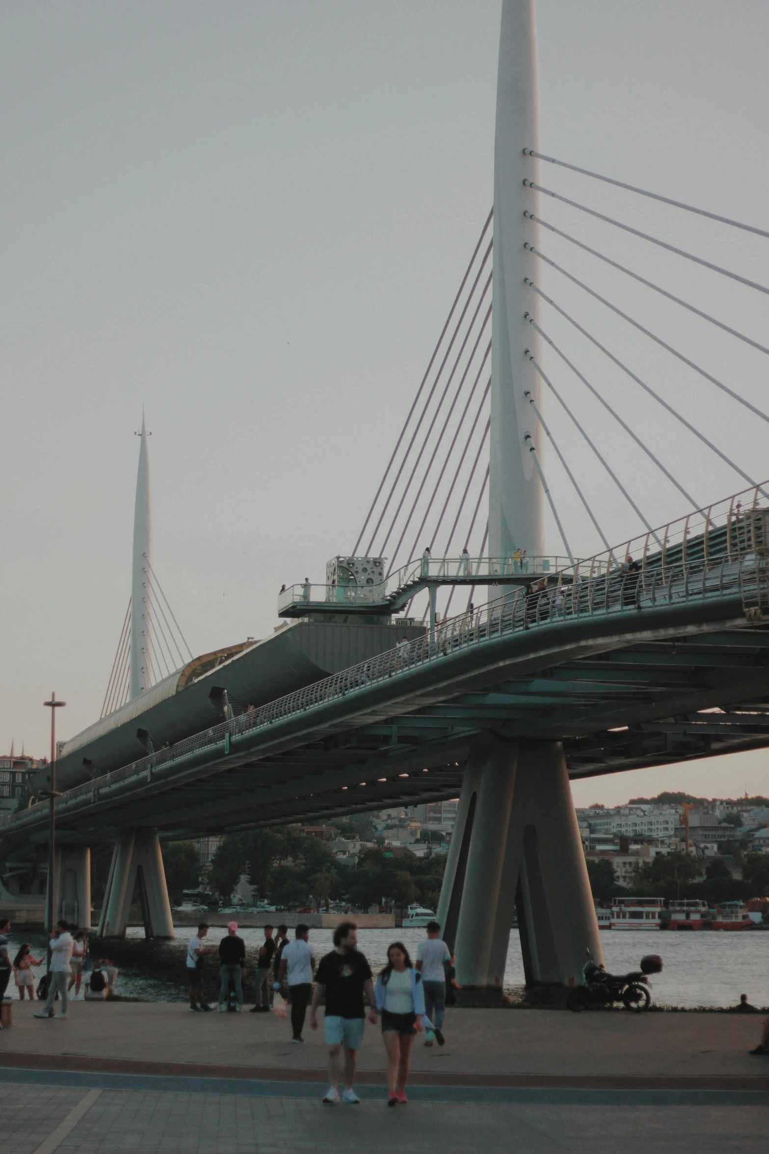 several people walk along the beach towards a bridge