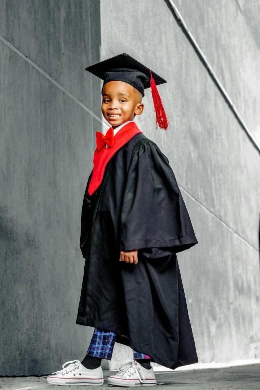 a young child is wearing graduation gown and red mortar