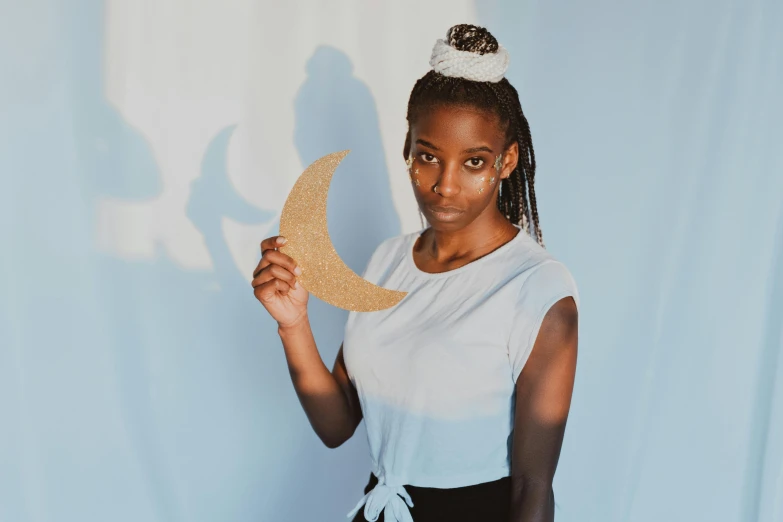 a woman holding a gold item in front of her face