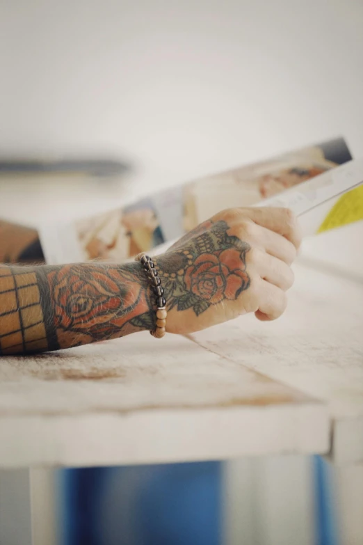 a tattooed arm reading a book sitting on a table