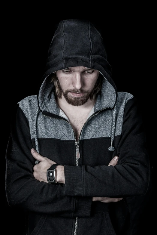 a man with his arms crossed wearing a hoodie