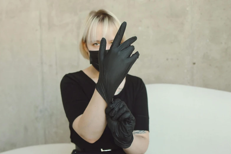 a girl sitting on a white couch wearing black leather gloves