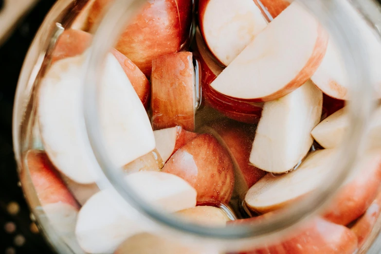 apples cut up in small pieces and peeled are placed inside a glass jar