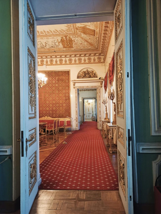 an ornate hallway leading to a living room with red carpet